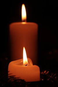 Close-up of burning candle against black background