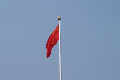 Low angle view of flag against clear blue sky