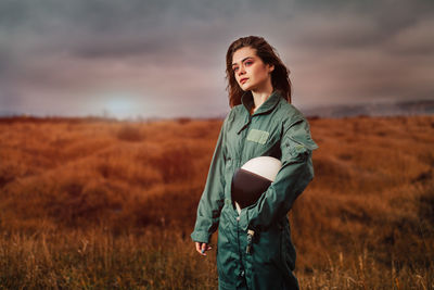 Young woman standing on field against sky during sunset
