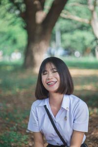 Portrait of smiling young woman sitting at park