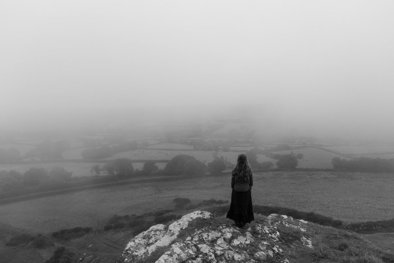 rear view, fog, real people, landscape, winter, standing, one person, women, nature, lifestyles, outdoors, beauty in nature, cold temperature, leisure activity, mountain, scenics, day, full length, sky, snow, warm clothing, young adult, adult, people