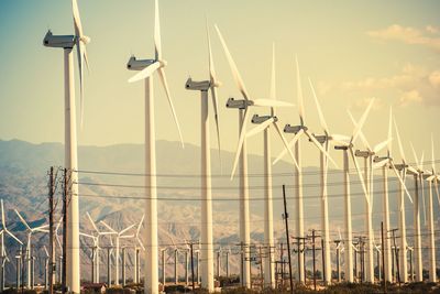 Windmills against mountains during sunset