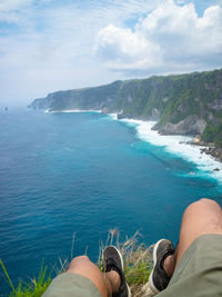 Low section of man on sea against sky