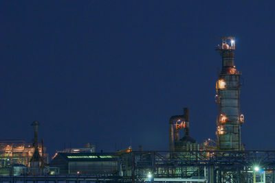 Illuminated factory against sky at night