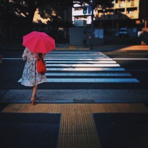 Rear view of woman walking on wet sidewalk