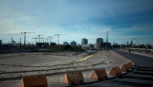 Road by buildings against sky in city