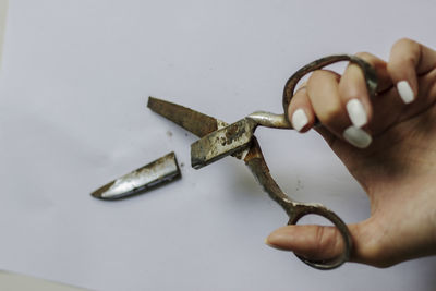 Cropped hand of woman holding broken scissors