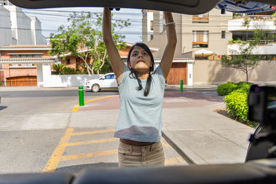 Rear view of woman with arms outstretched standing on street