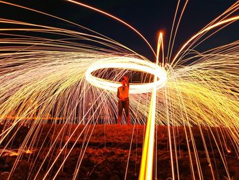 Man spinning illuminated wire wool at night