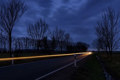Road by trees against sky at night