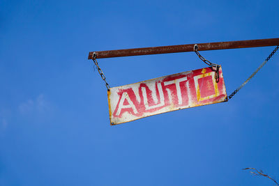 Low angle view of information sign hanging against clear blue sky