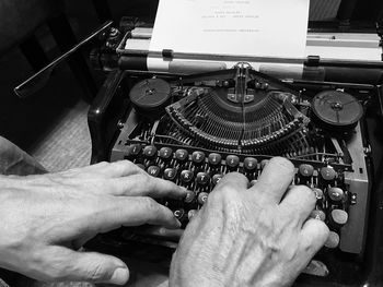 Cropped hands of man using typewriter