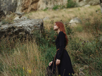 Side view of young woman standing on field