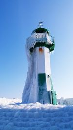 Low angle view of snow covered lighthouse against sky