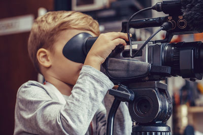 Small kid using video camera while filming in movie studio.