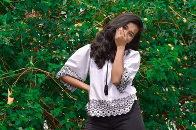 Beautiful young woman standing against plants