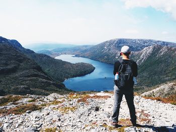 Rear view of man standing on mountain against sky