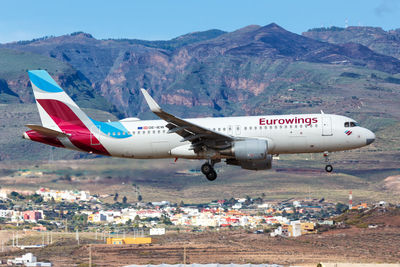 Airplane flying over mountains against sky