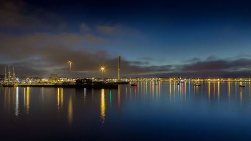 Illuminated harbor by sea against sky at night