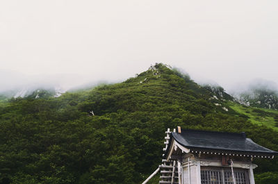 House amidst trees and buildings against sky