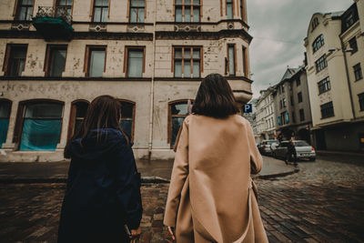 Rear view of people walking on street against buildings