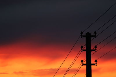 Low angle view of silhouette electricity pylon against sky during sunset