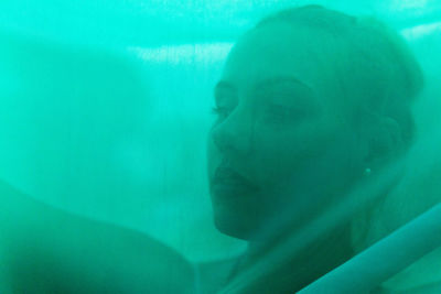 Close-up of thoughtful young woman with face covered by green scarf