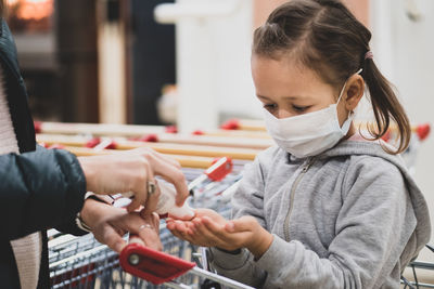 Mother giving hand sanitizer to daughter at supermarket