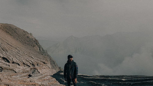 Rear view of man standing on mountain against sky