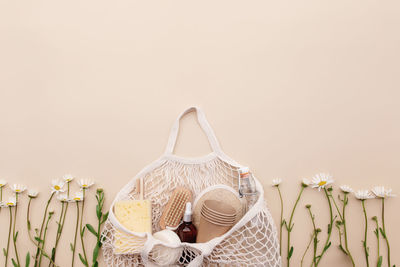 Eco friendly summer concept on beige background with eco shopping bag, white chamomile flowers