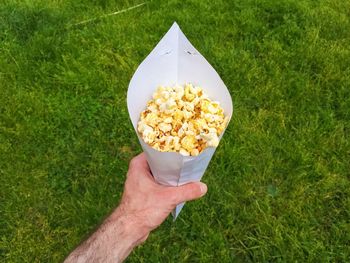 Cropped image of man holding popcorn in paper cone