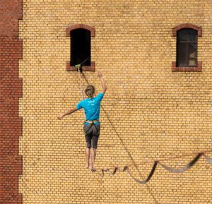 Full length rear view of man walking on brick wall