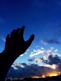 Silhouette of hand against sky at night