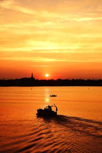 Silhouette boat in sea against sky during sunset