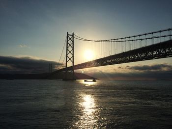 Suspension bridge over river at sunset