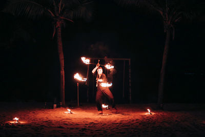 People standing by illuminated fire at night