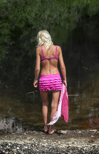 Rear view of woman standing against pond