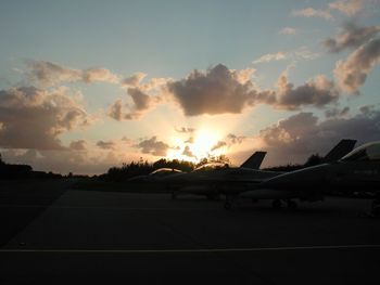 Airplane on runway against sky during sunset