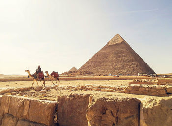 Low angle view of people walking on mountain against clear sky