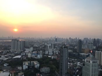 Aerial view of city buildings against sky during sunset