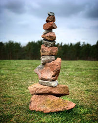 Stack of stones on field against sky