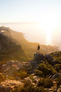 High angle view of man on rock looking at sea