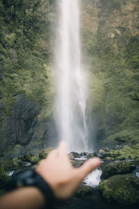 Low section of man standing against waterfall