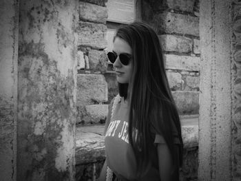 Side view of woman wearing sunglasses against wall