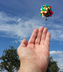 Low angle view of hand holding flower against sky