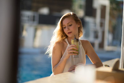 Young woman having drink at sidewalk cafe