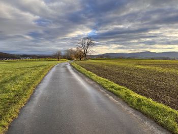 Road amidst field against sky