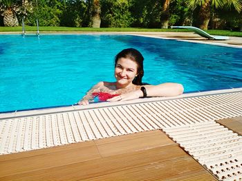 Portrait of smiling young woman in swimming pool on sunny day