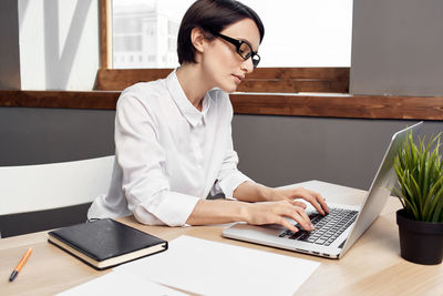 Woman using phone while sitting on table