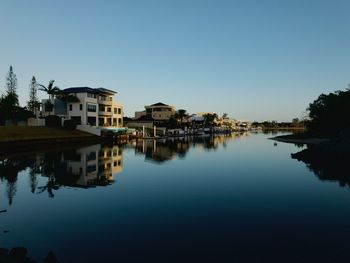 Reflection of buildings in lake against clear sky